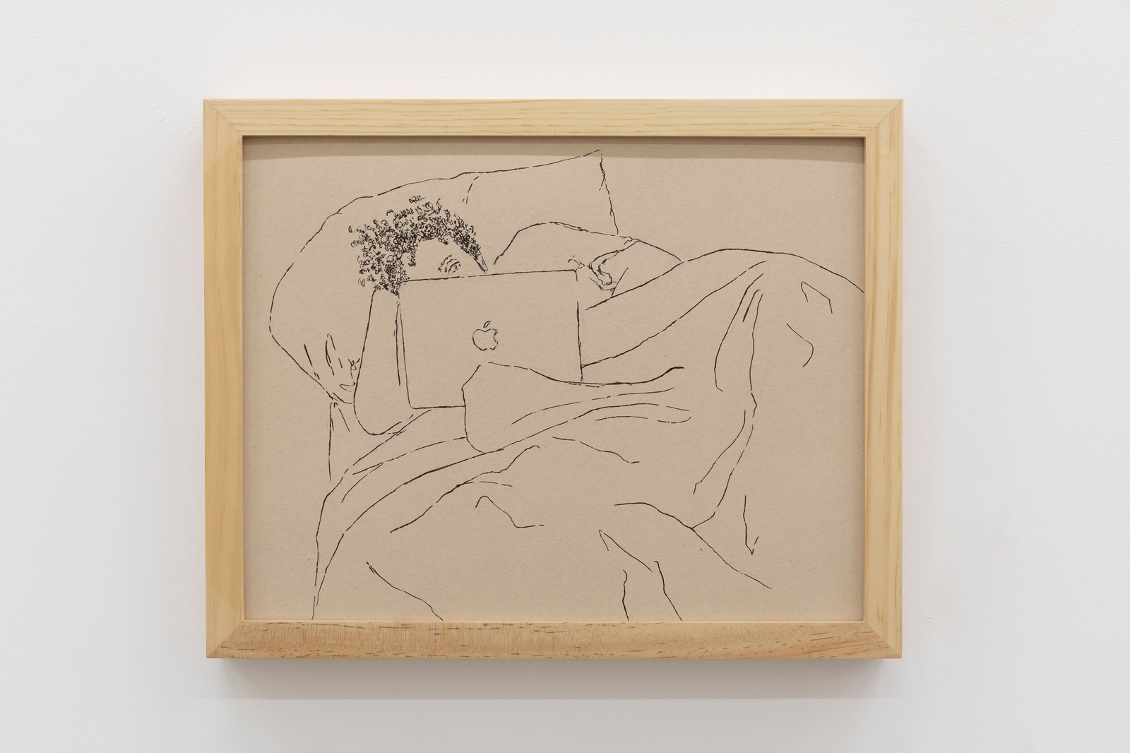 [A close-up view of a line drawing in black pen on brown-toned paper in a light wooden frame. The drawing is of a person with tightly coiled curly hair resting in bed while looking at an Apple brand laptop. The figure lays on a pillow with their head propped up by their hand. Their face is mostly obscured by the laptop revealing only one eye. Their body is covered in a blanket. The folds of the blanket take up half of the surface of the drawing.]